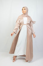 A woman wearing a beige and white kimono set with stone work on the cuffs, paired with a matching headscarf.