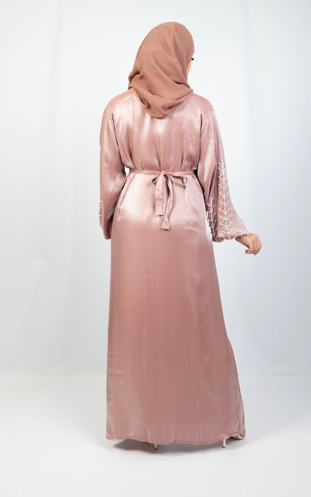 A woman wearing a pink and white kimono set with stone work on the cuffs, paired with a matching headscarf.