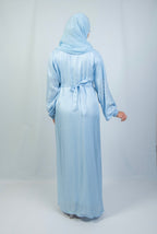 A woman wearing a blue kimono set with white stone work on the cuffs, standing against a plain background.